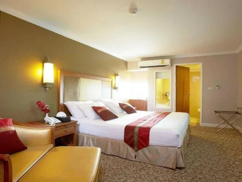 Hotel room with a large bed, bedside tables, seating area, and open door to a bathroom.