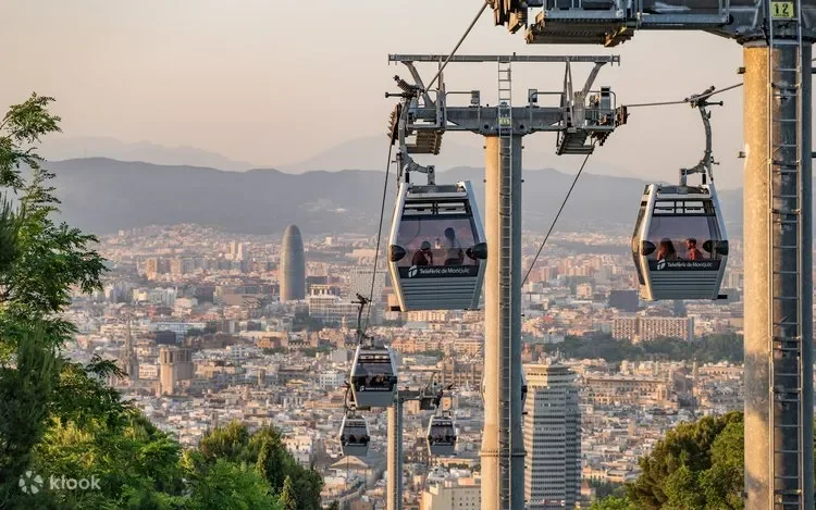 City skyline with buildings and mountains in the distance, with a cable car system in the foreground.