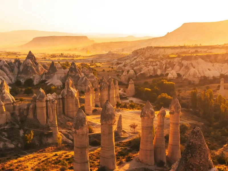 Rock formations in Cappadocia, Turkey, during sunset with warm lighting and a clear sky.