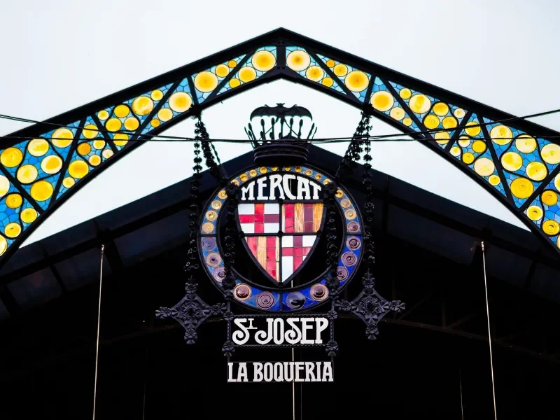 Decorative sign with a shield crest, the word 'MERCAT,' and the text 'S. JOSEP LA BOQUERIA.'