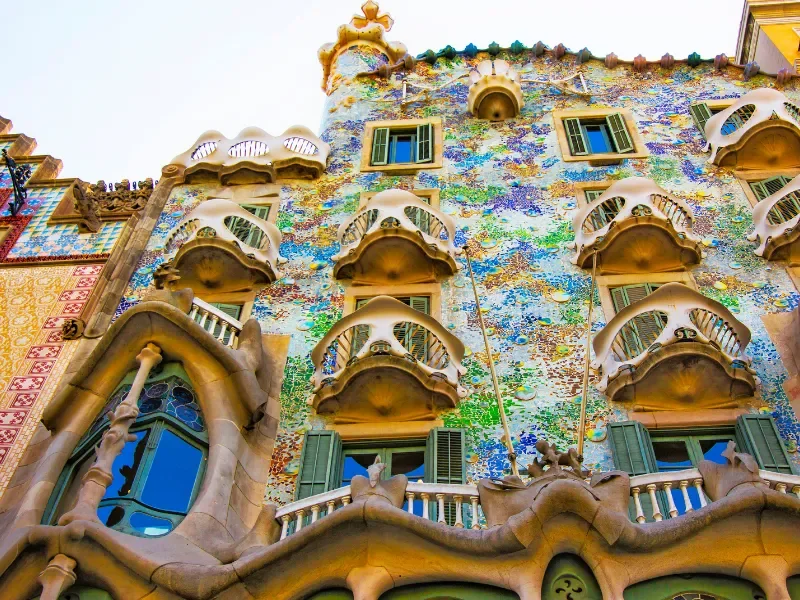 The colorful, ornate facade of Casa Batlló, a famous building in Barcelona designed by Antoni Gaudí, featuring irregular windows, balconies, and vibrant mosaic tiles.