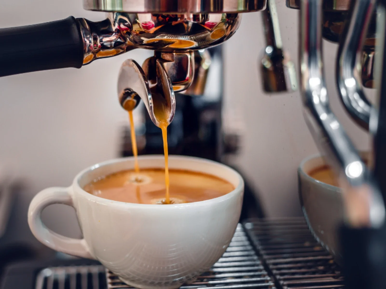 Espresso machine pouring coffee into a white ceramic cup.