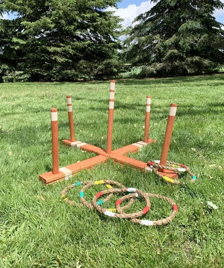 A game of lawn horseshoes set up on a grassy lawn with trees in the background.