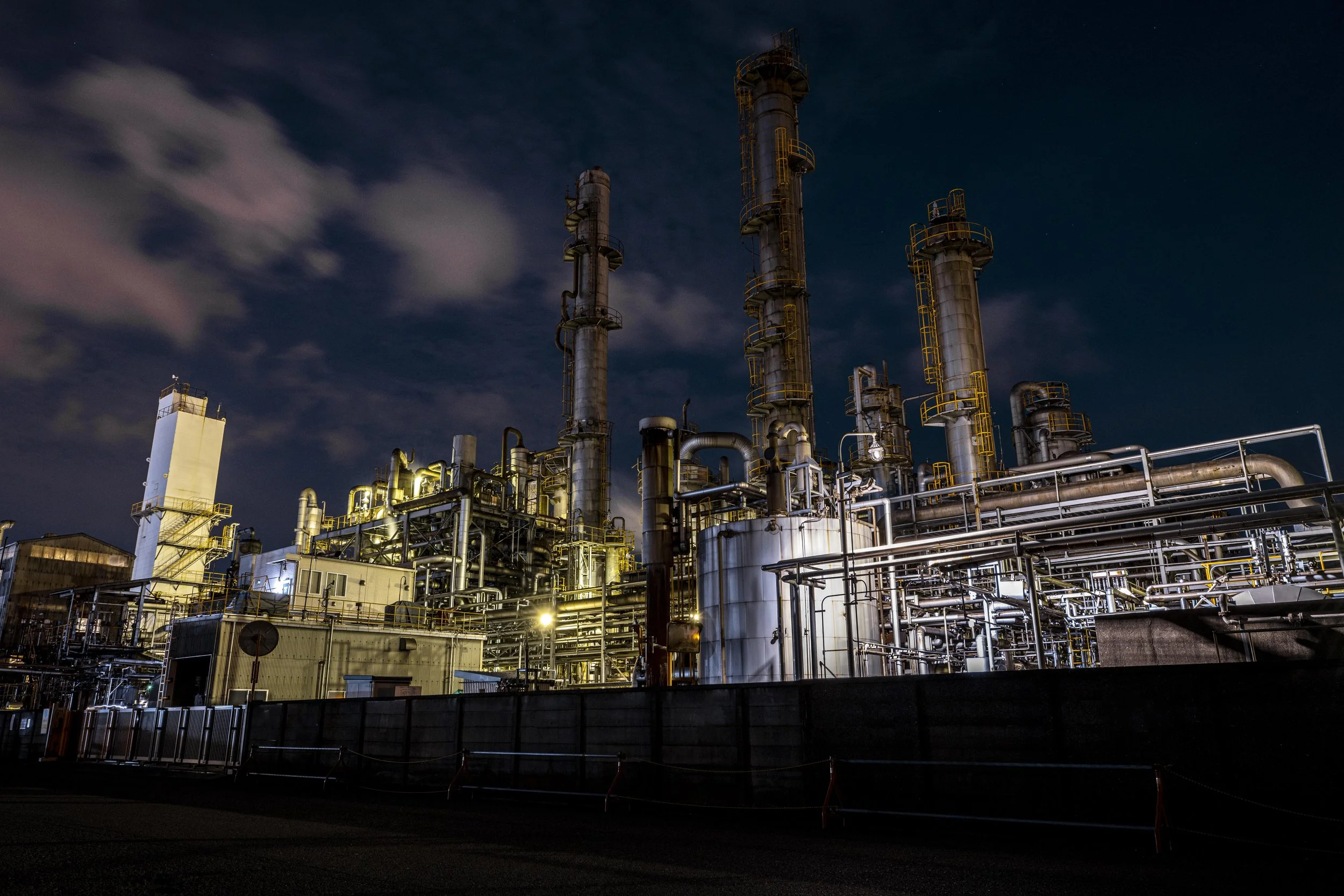 Industrial refinery at night with illuminated pipes and tall towers