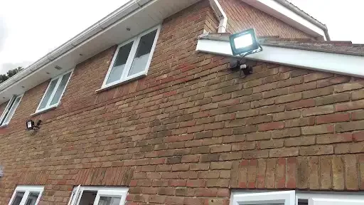 Close-up of the exterior of a brick house showing windows and a light fixture.
