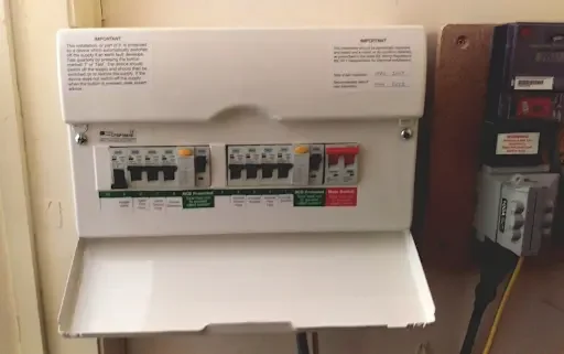 Electrical circuit breaker panel with switches and labels, mounted on a wall.