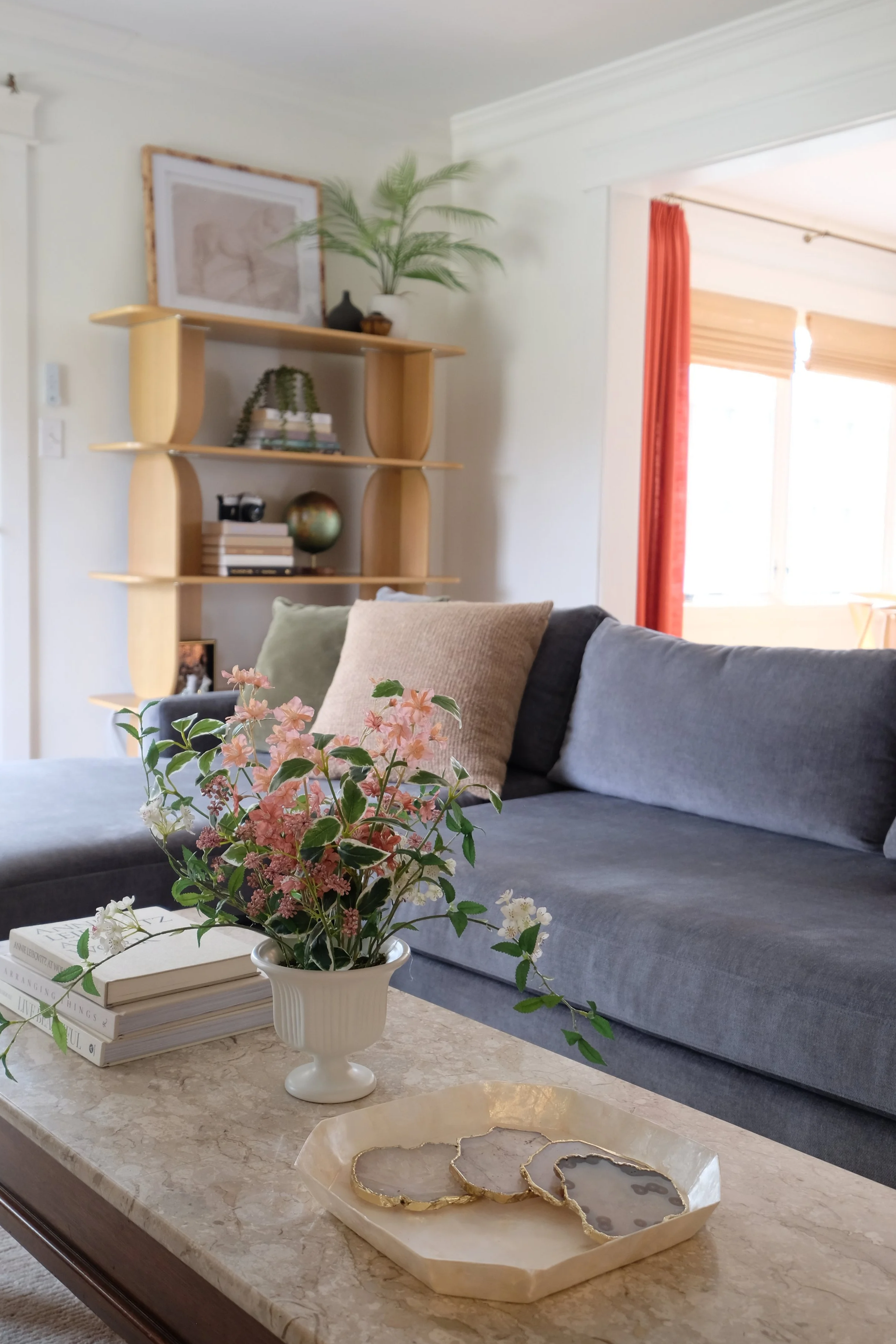 Marble and wood coffee table styled with fresh flowers, stacked books, and agate coasters