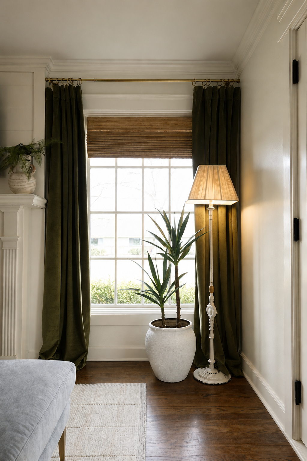 Window nook with olive curtains, a woven Roman shade, and a floor lamp beside a potted yucca