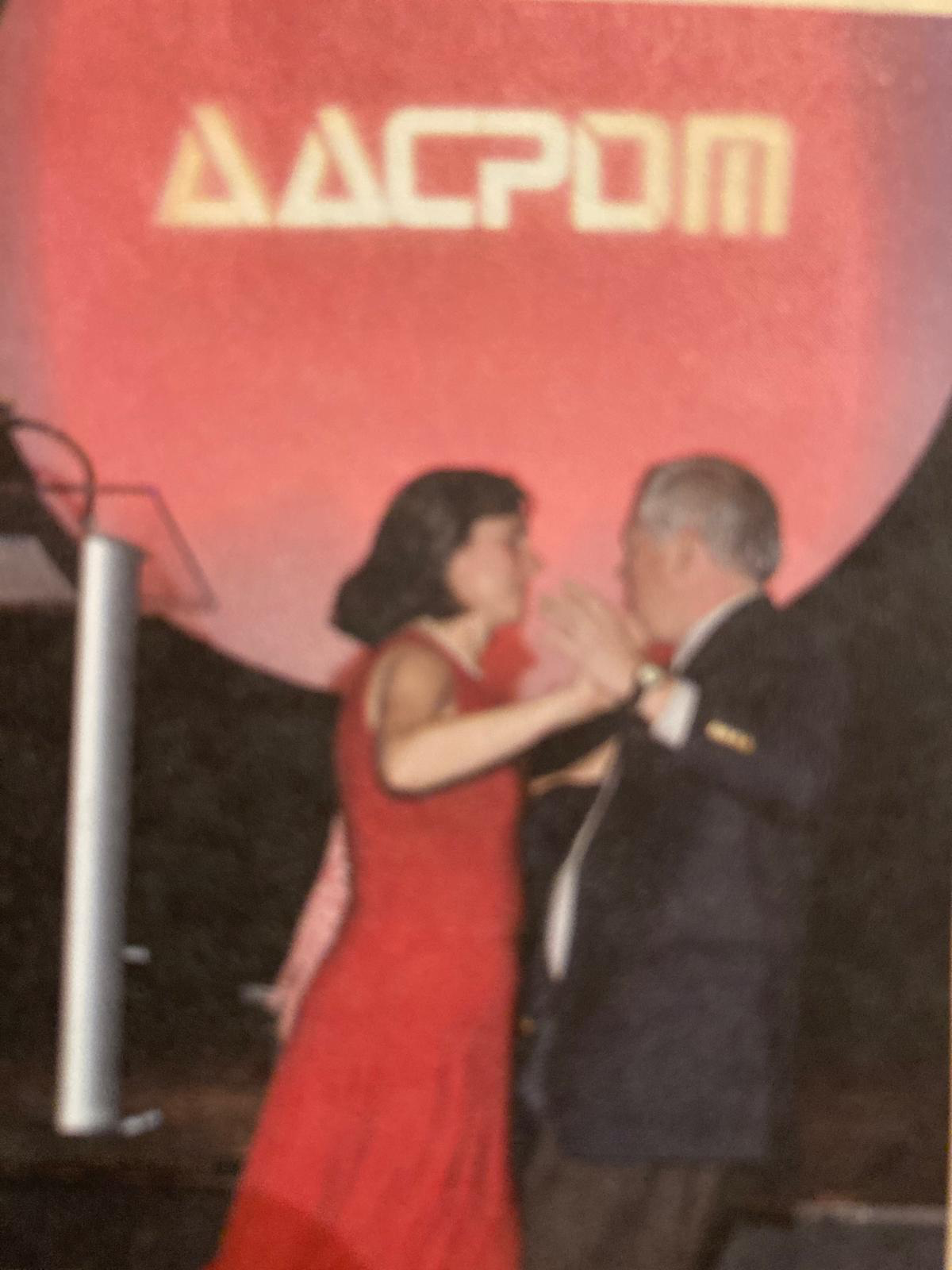 Joe and Karen dancing in front of the AACPDM logo. 