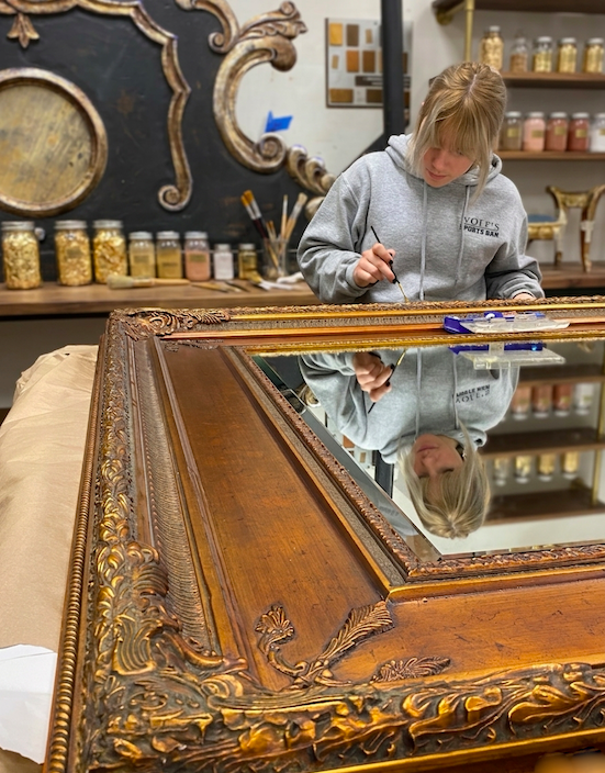 Technical restoration of a gold leaf mirror frame for a luxury boutique hotel. Tilia Design Co. specialist performing precision gilding and wood repair on-site in Dallas.