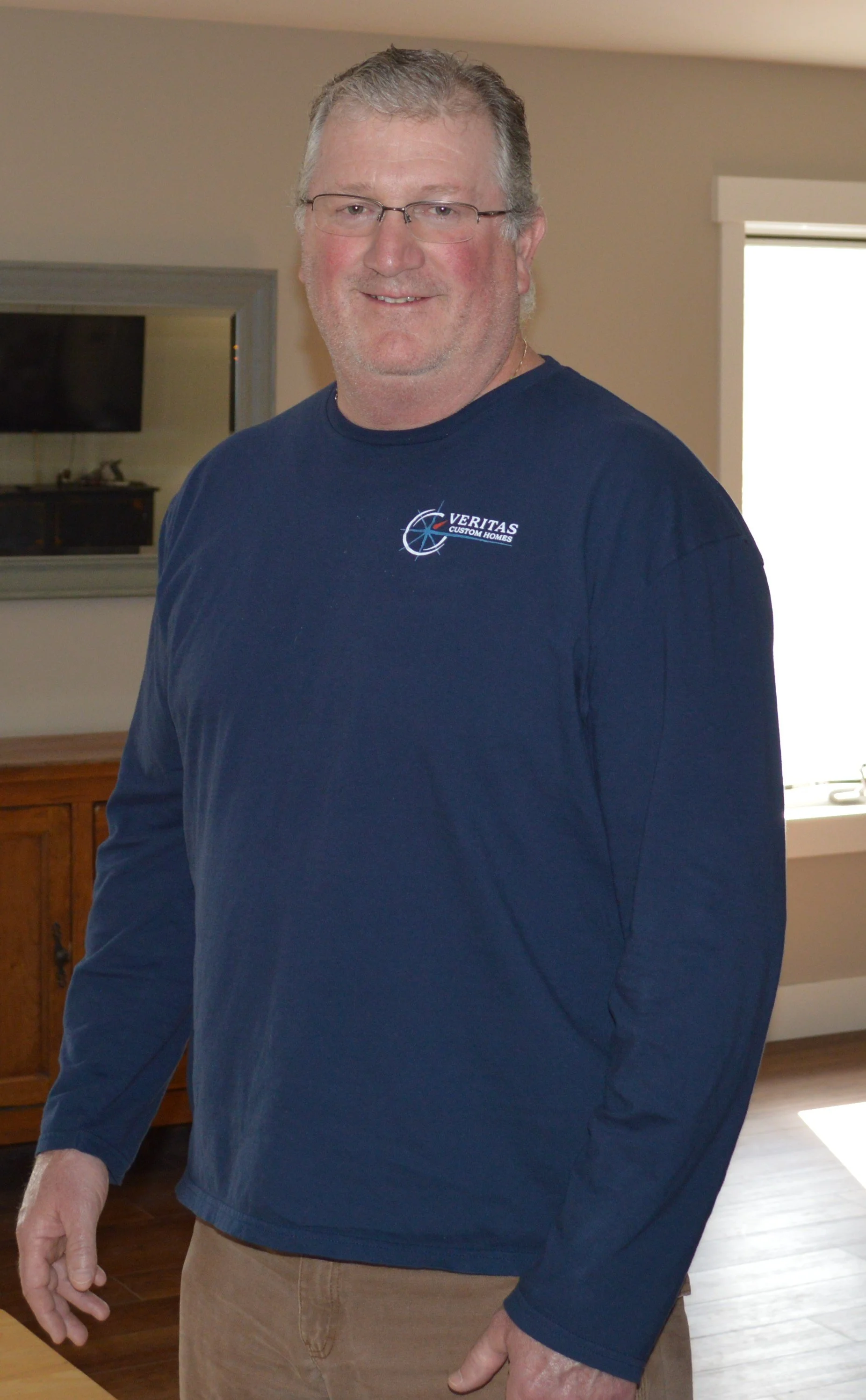 Tim Klink is a smiling older man with glasses standing indoors.