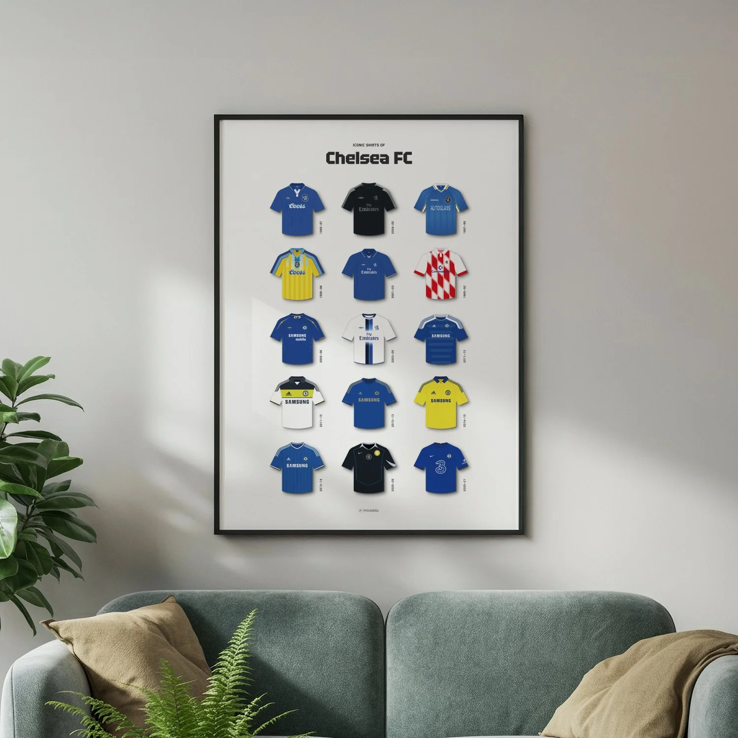 Chelsea FC football shirt history poster in a black frame hanging on a white wall above a teal sofa.