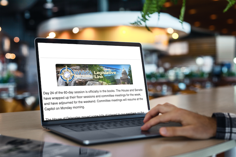 A person using a laptop showing a legislative link website with the U.S. Capitol in the header, in a café or open workspace.
