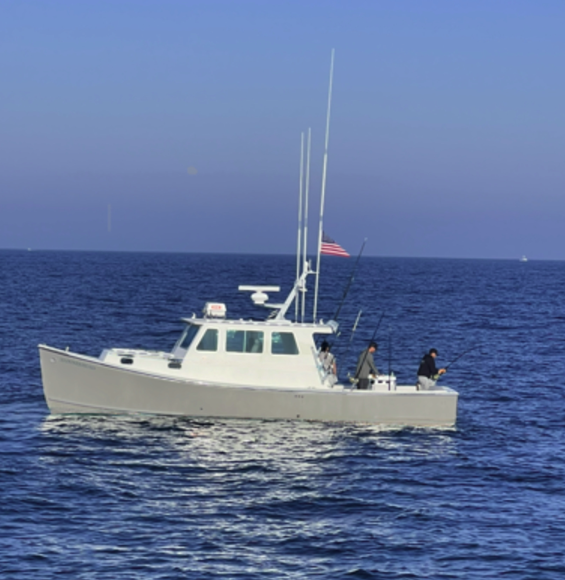 A white fishing boat on the ocean with three people on board, fishing gear, a radar, and an American flag at the stern.