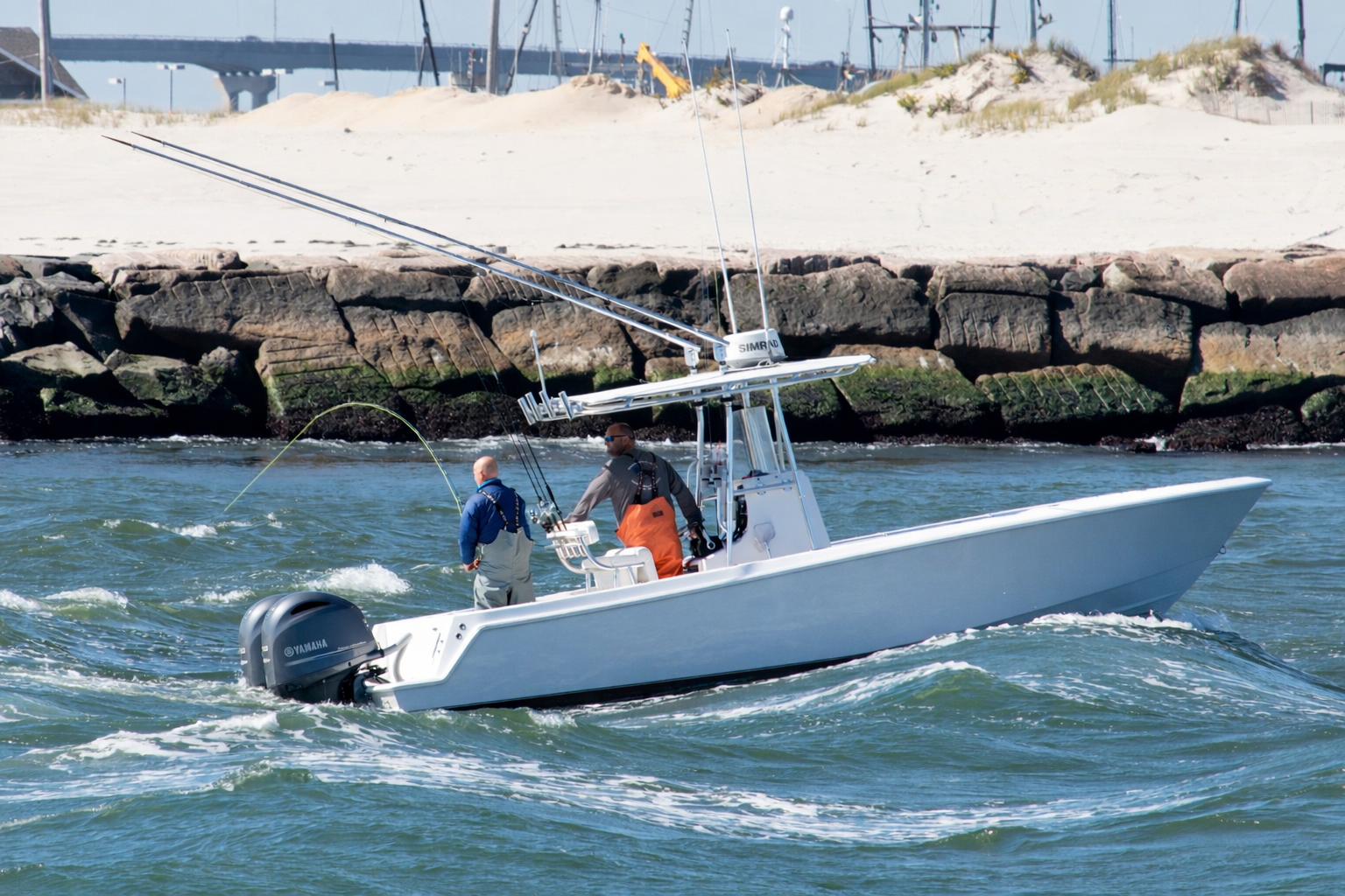 Two men fishing from a white boat in the Hamptons during a fishing charter