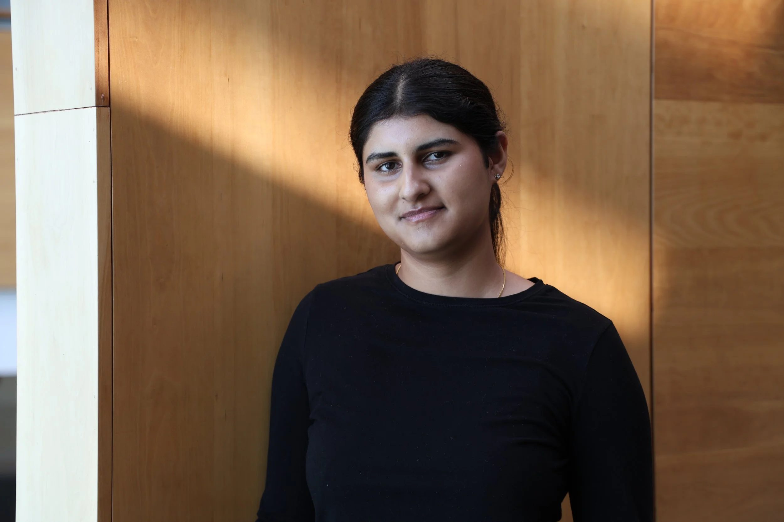 A woman smiling with a black hair and black shirt.