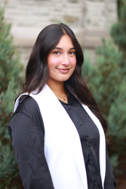 A woman on black straight hair smiling with a white and black shirt.