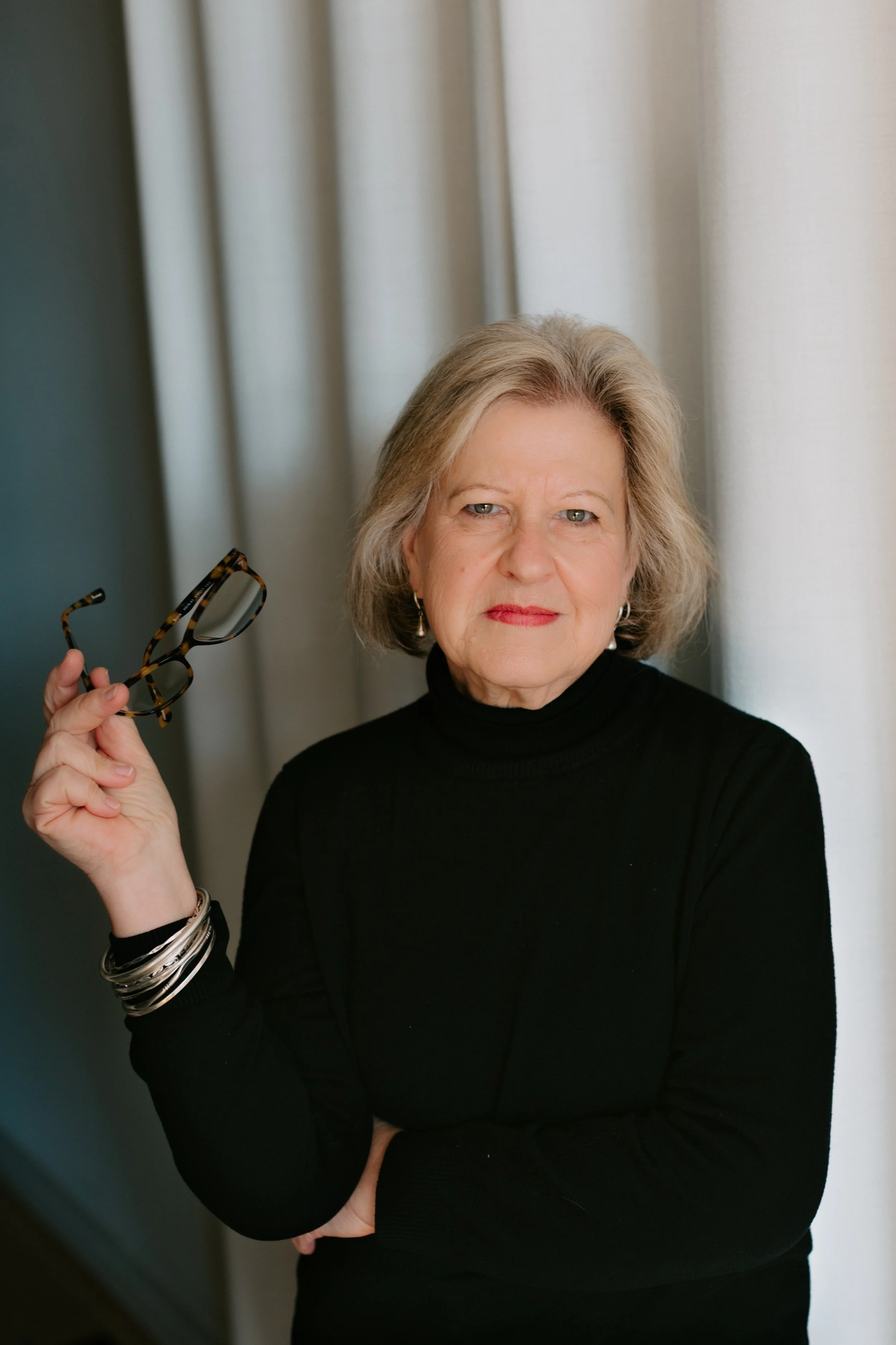 A photo of an Intellectual Property Ontario Board Member wearing black long sleeves while holding her glasses