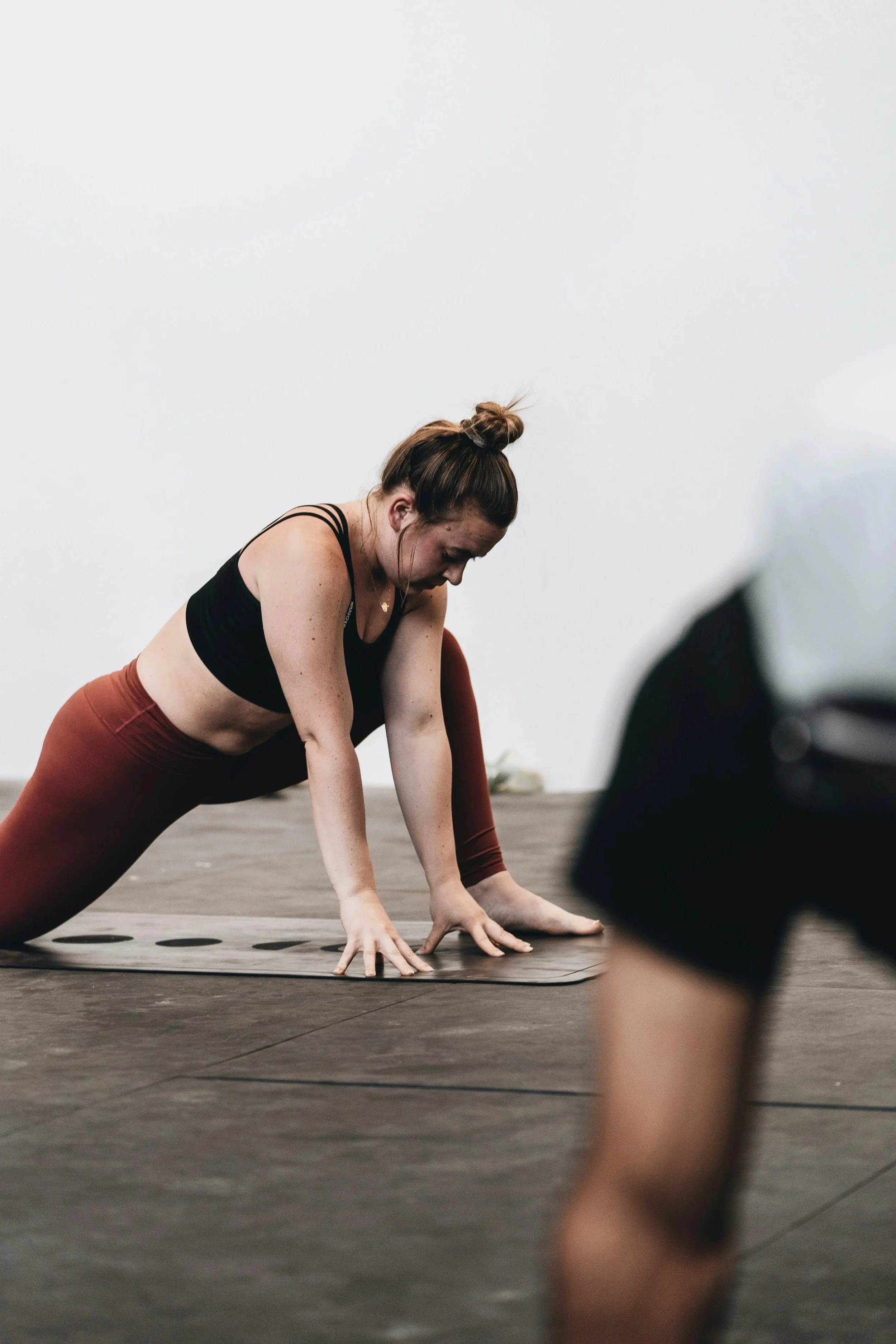 Une femme en tenue de sport fait du yoga ou de la marche en position de planche sur un tapis dans une salle