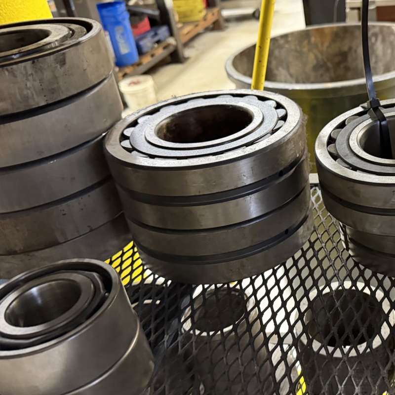 Stacks of large industrial ball bearings on a metal table in a workshop.