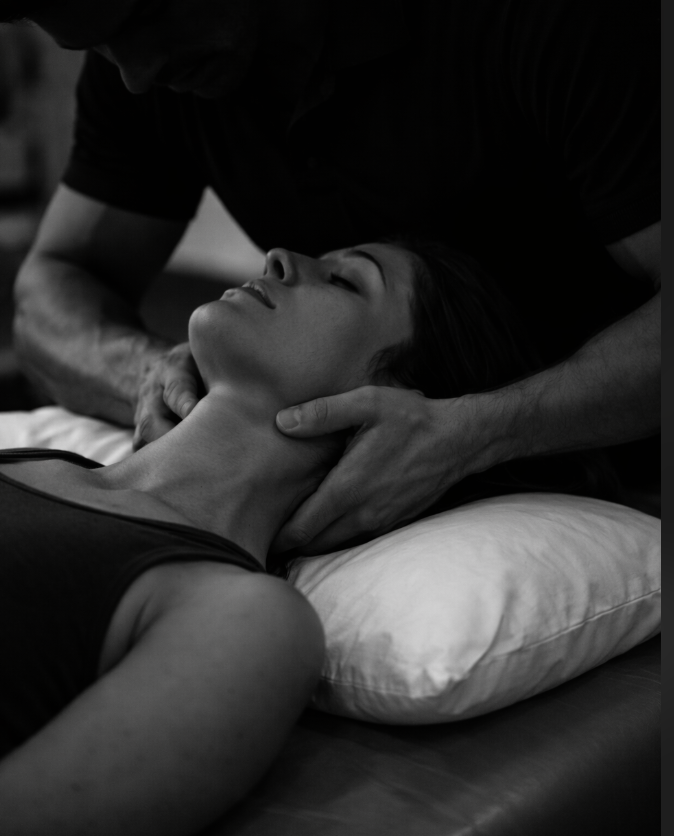 Black and white photo of a woman receiving chiropractic adjustment or neck therapy from a practitioner.