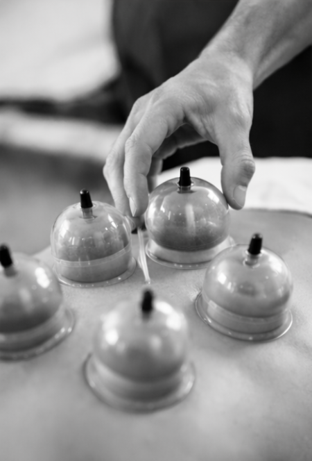 A person's hand is seen placing an object on a translucent plastic dome covering a small item on a table.