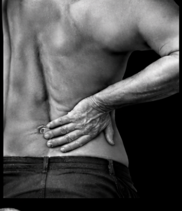 A person holding their lower back with their right hand, showing back pain or discomfort.