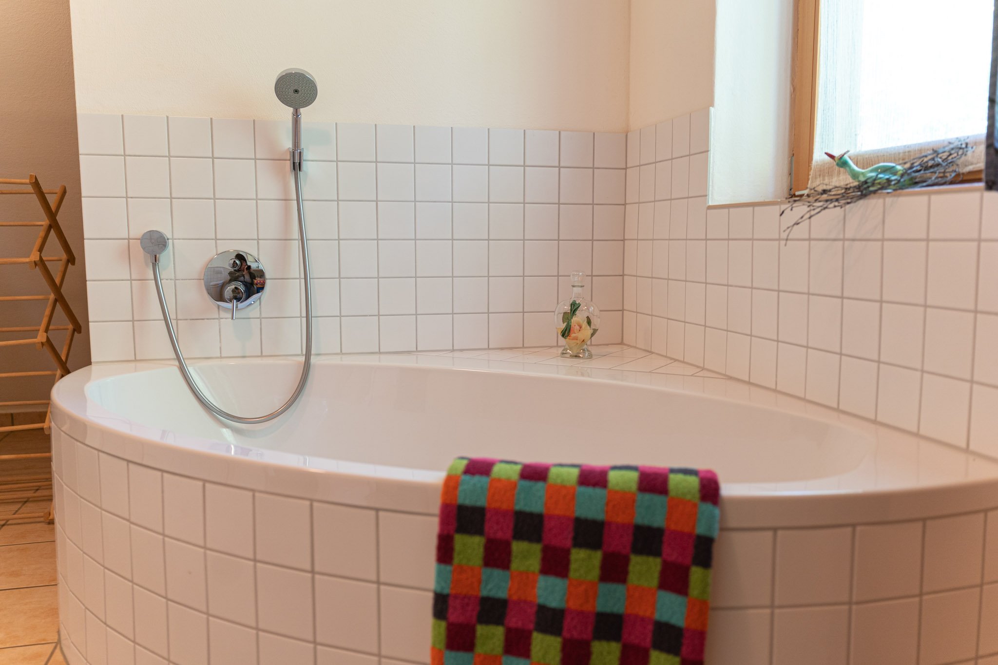 Badezimmer mit Badewanne, Handtuch, Deko-Objekte und Fenstersims.