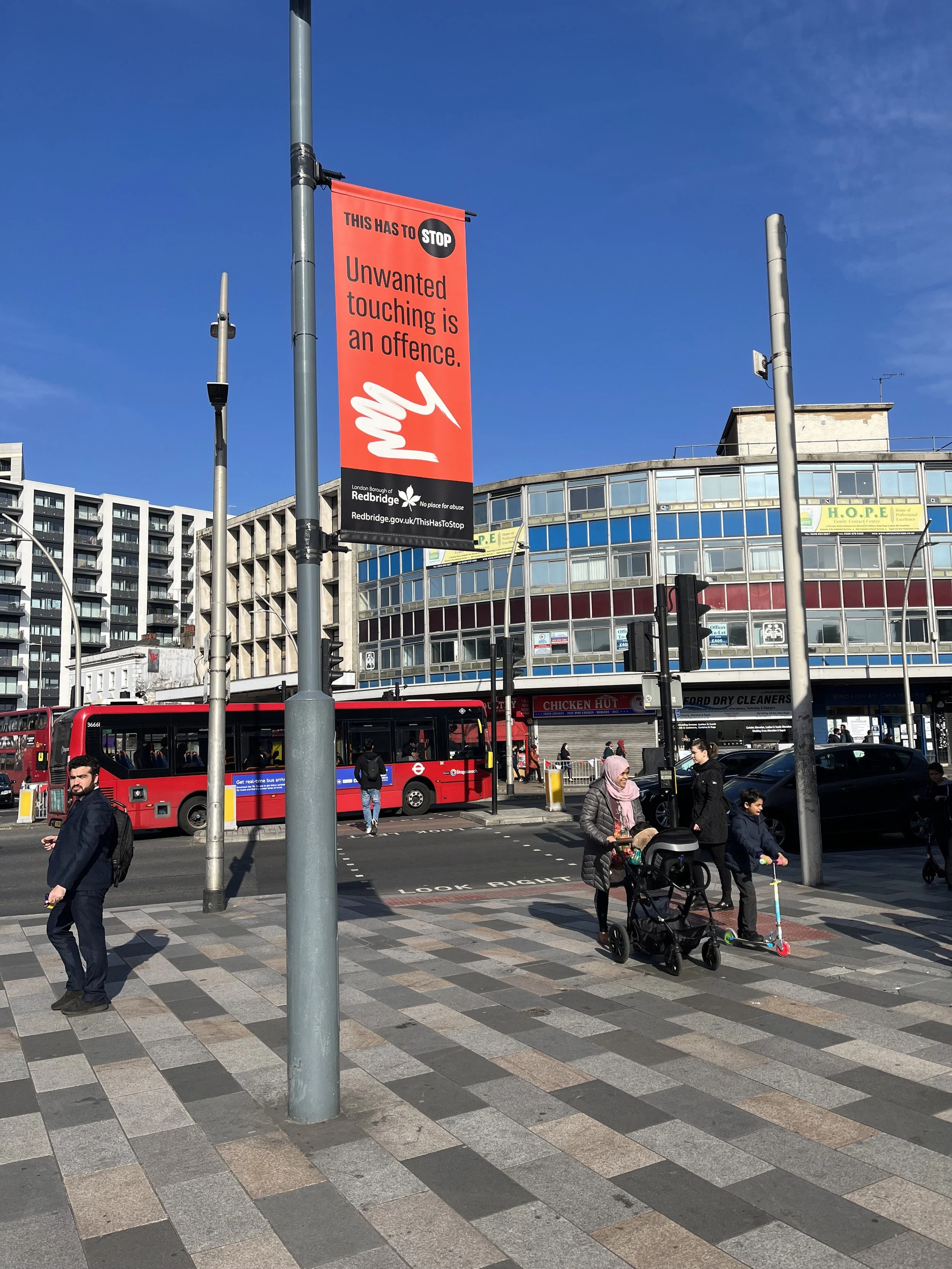 A view of a busy Redbridge street with a ThisHasToSTOP banner that reads 'Unwanted touching is an offence.'