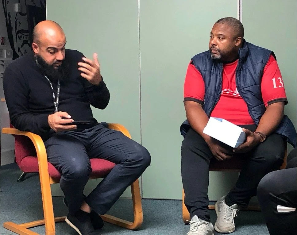 Two man sat down, having a conversation.