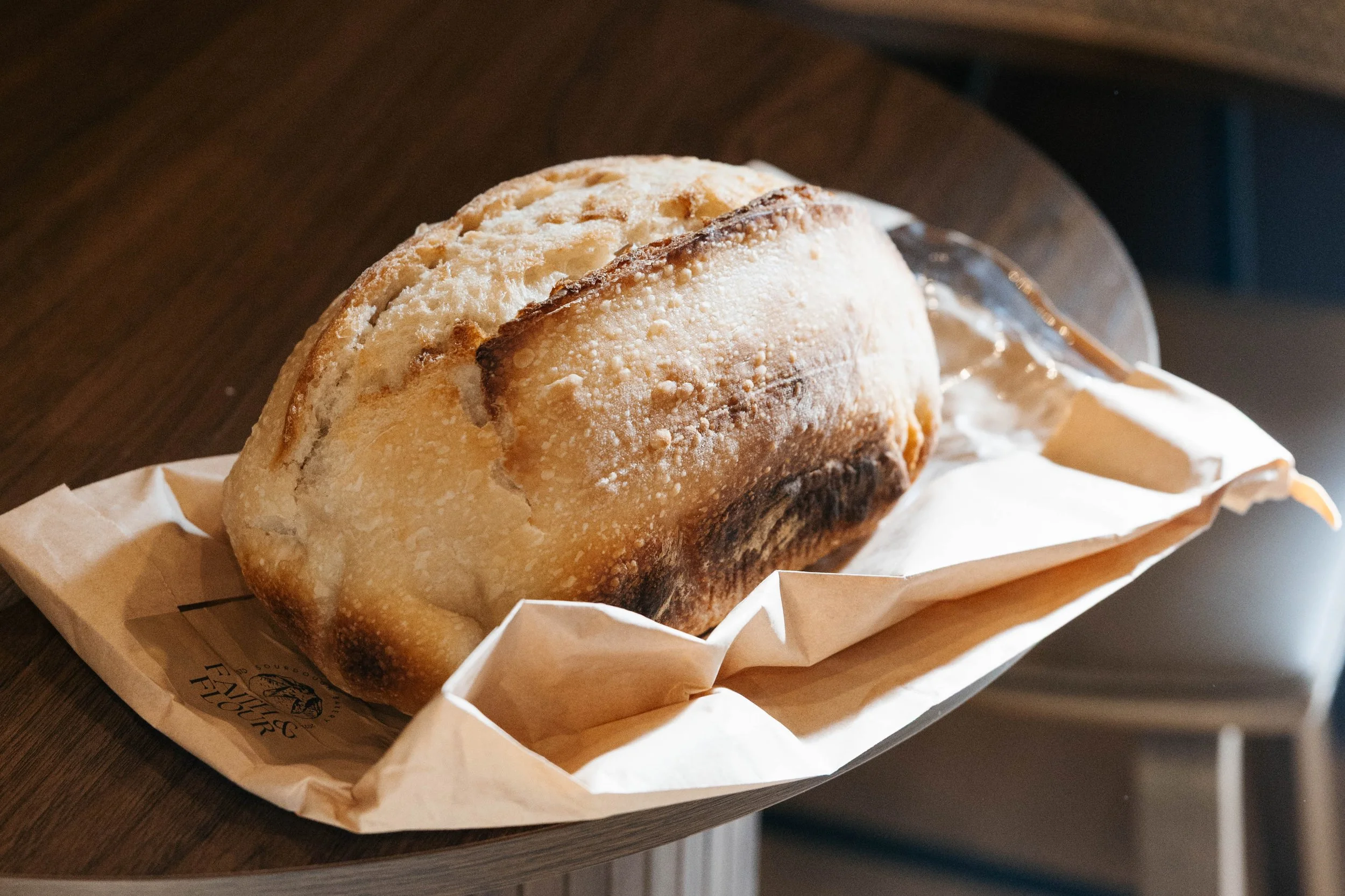 Chocolate muffin with chocolate chips in baking paper liner, inside a beige bowl with orange rim.