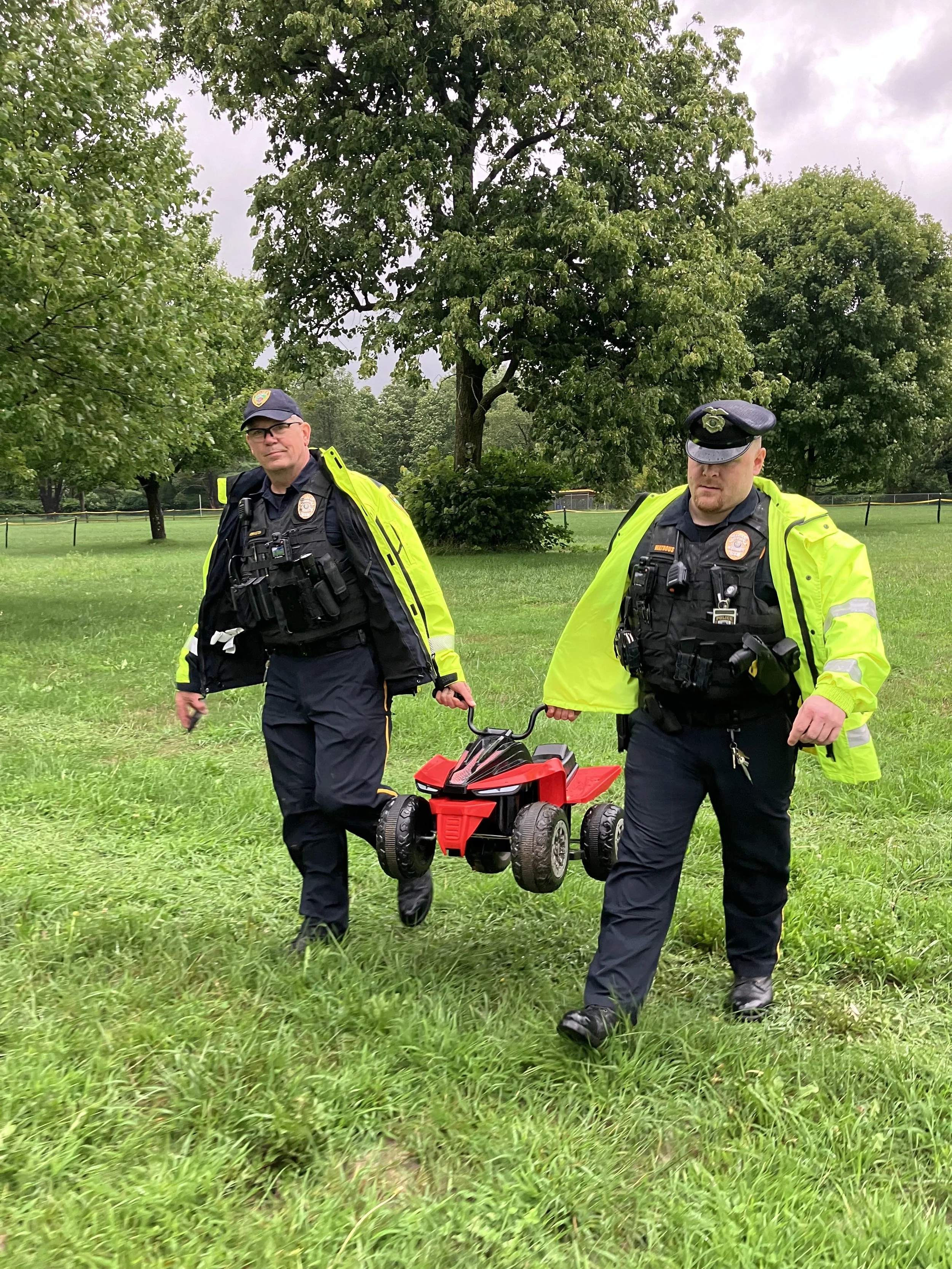 Two uniformed officers carrying a toy vehicle