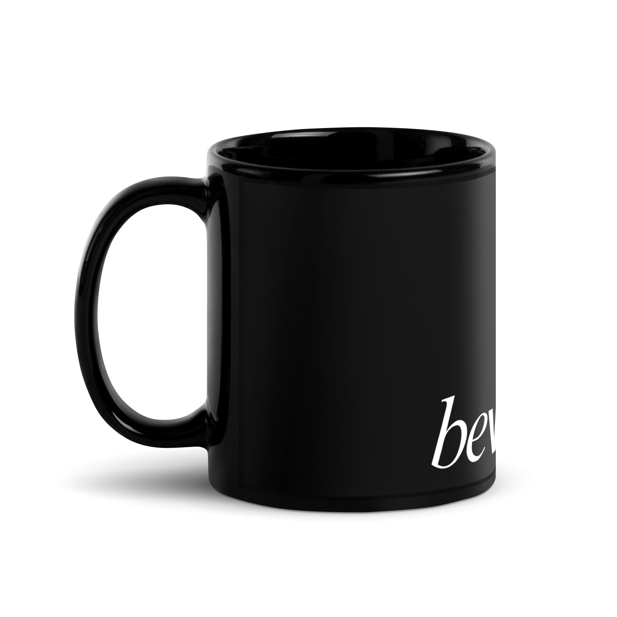 The Mug - Black Mug, side view. Shows the handle and partial white text starting with 'be'.