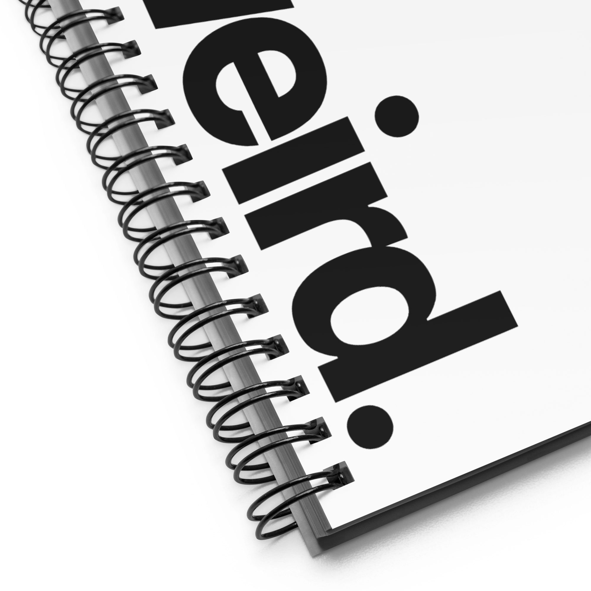 Notebook - Close-up detail of white spiral notebook. Highlights the black wire binding and serif typography.