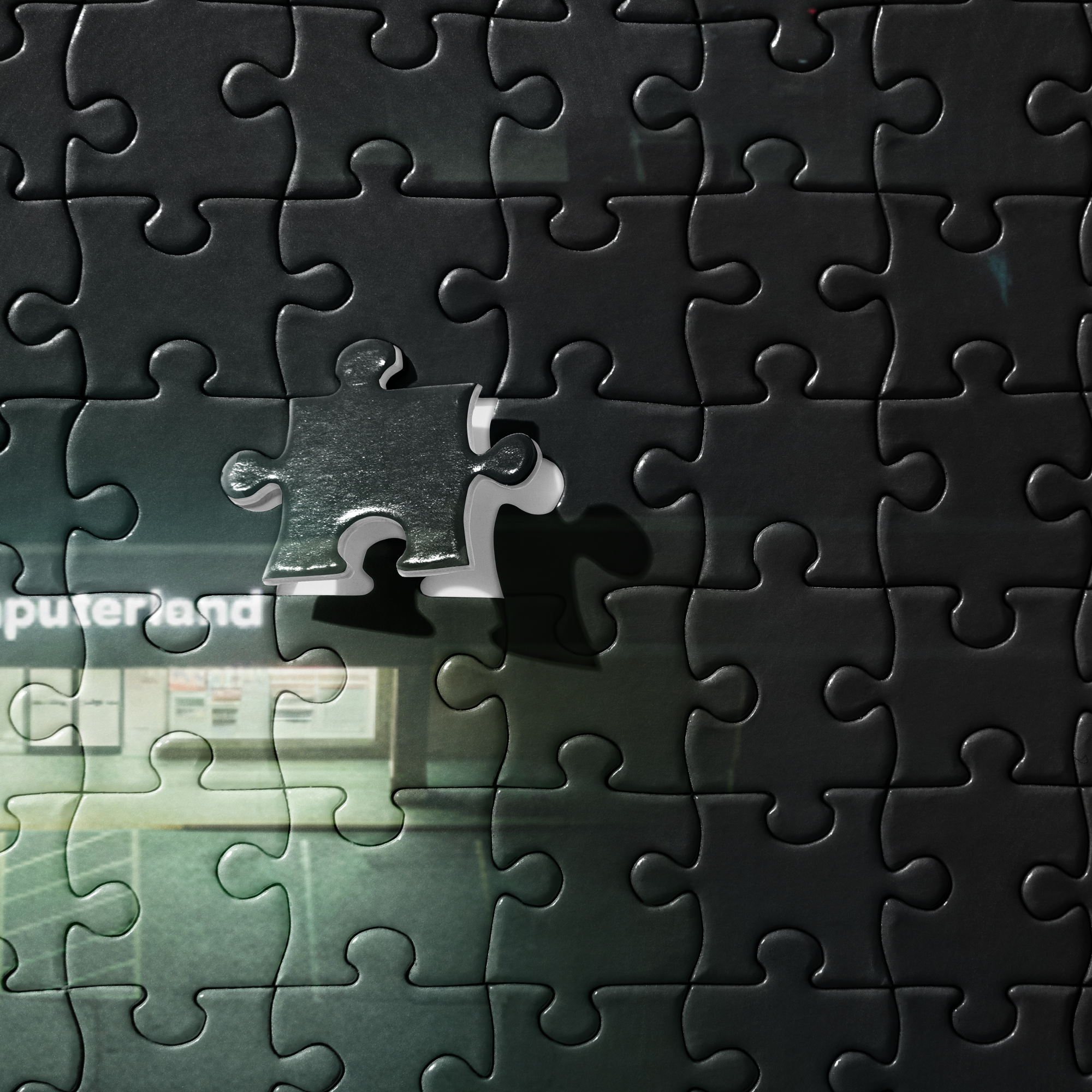 Puzzle - Fluorescent - Close-up detail of jigsaw puzzle pieces. Highlights the texture of the dark interlocking pieces and the white lettering of the sign.
