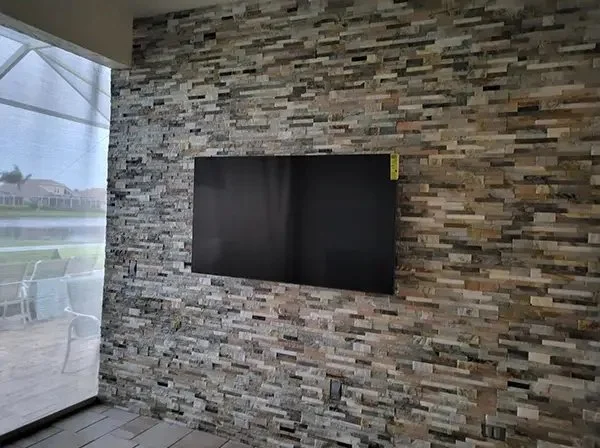 Flat-screen TV mounted on a stone accent wall in a modern living room.