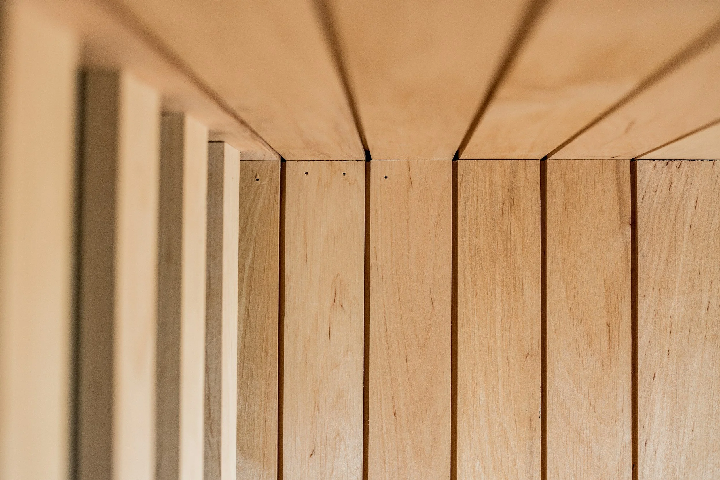 Close-up view of a wooden slat wall or paneling with vertical and horizontal wooden planks.