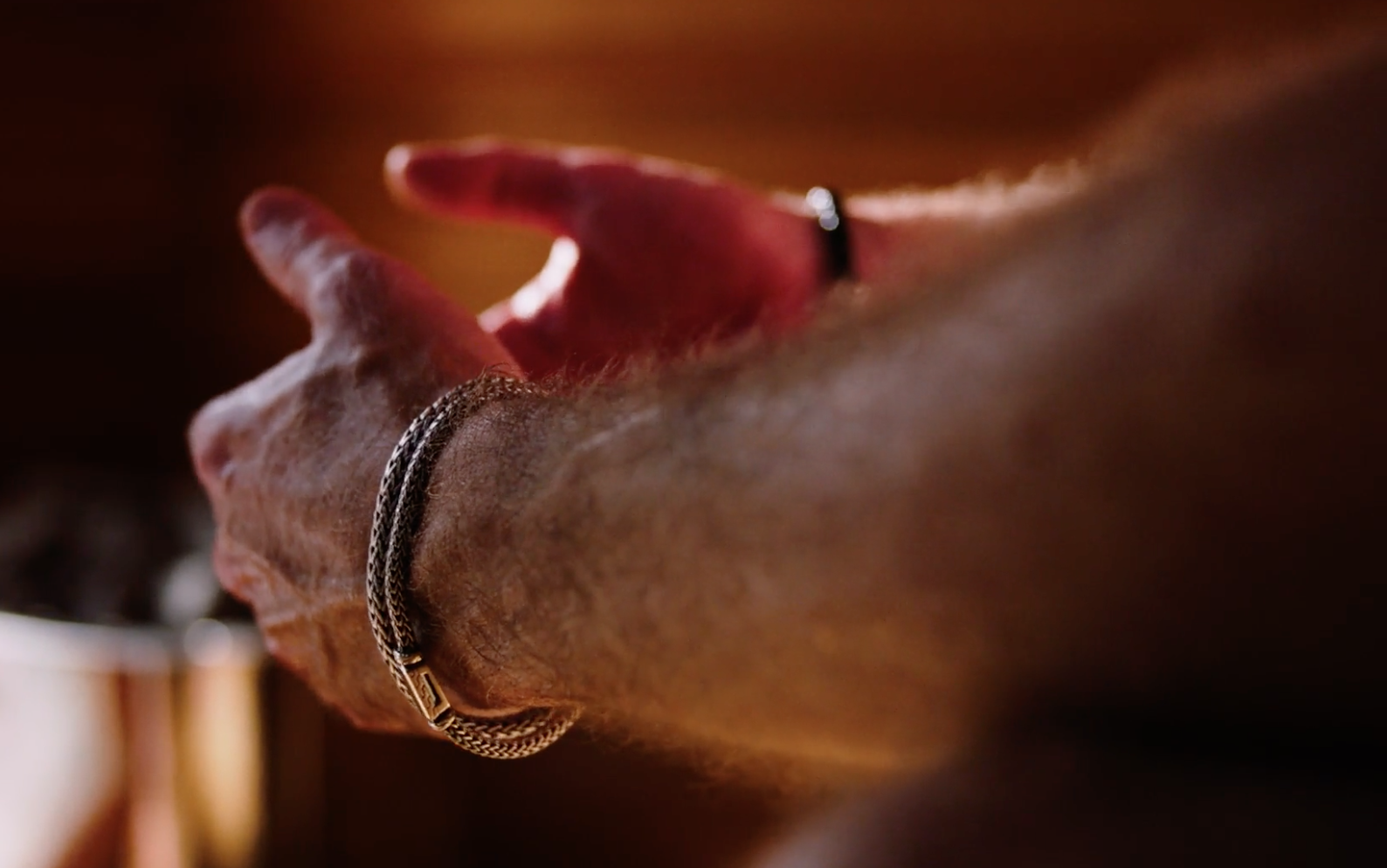 Close-up of a person's hand wearing a silver bracelet, with a blurred background.