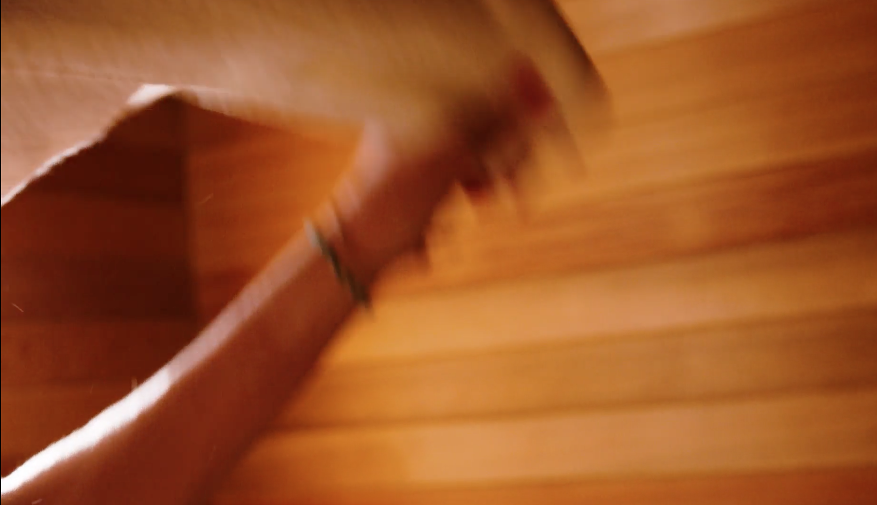 Blurred photo of a person in a sauna, with wooden walls, seen from below, with motion blur.
