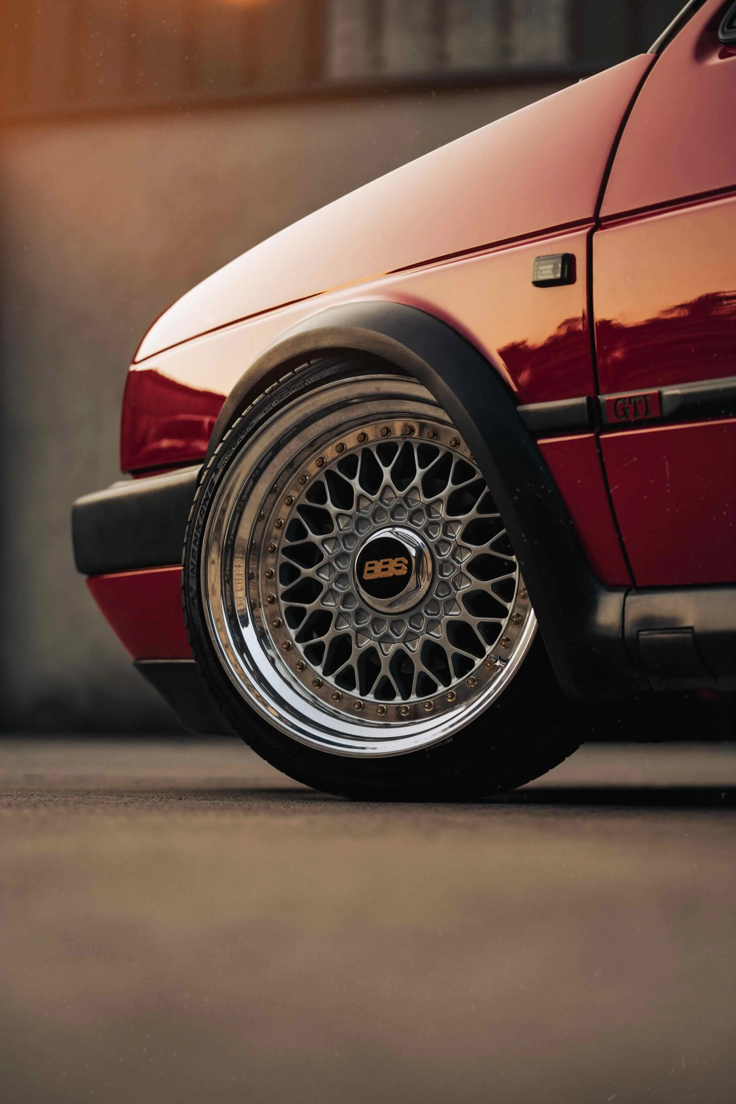 Close-up of a red sports car's front wheel, featuring a BBS mesh alloy rim, with a sleek bodywork and the GTI badge.