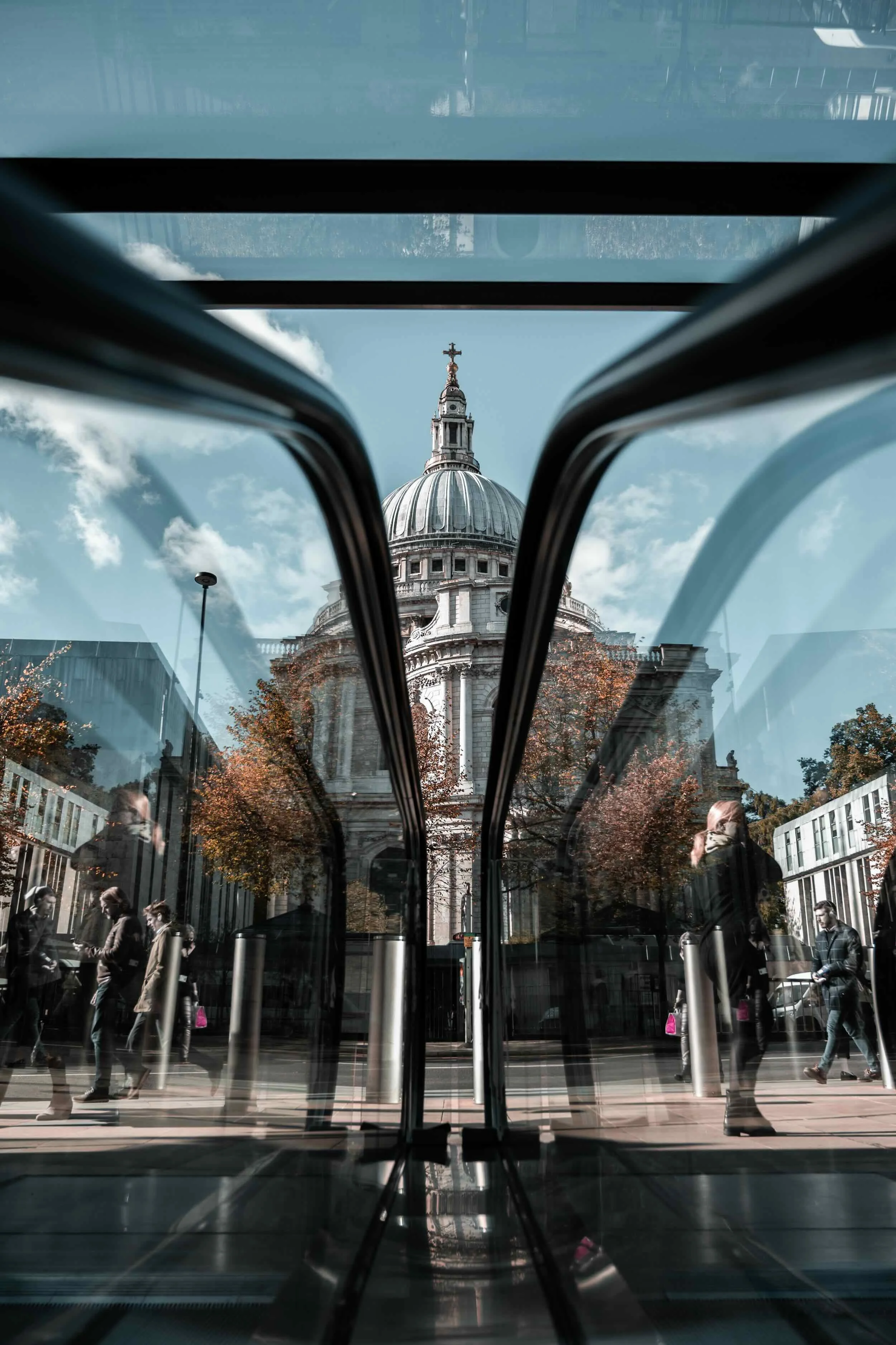 View of St. Paul's Cathedral through the glass doors of a bus stop in London on a sunny day.