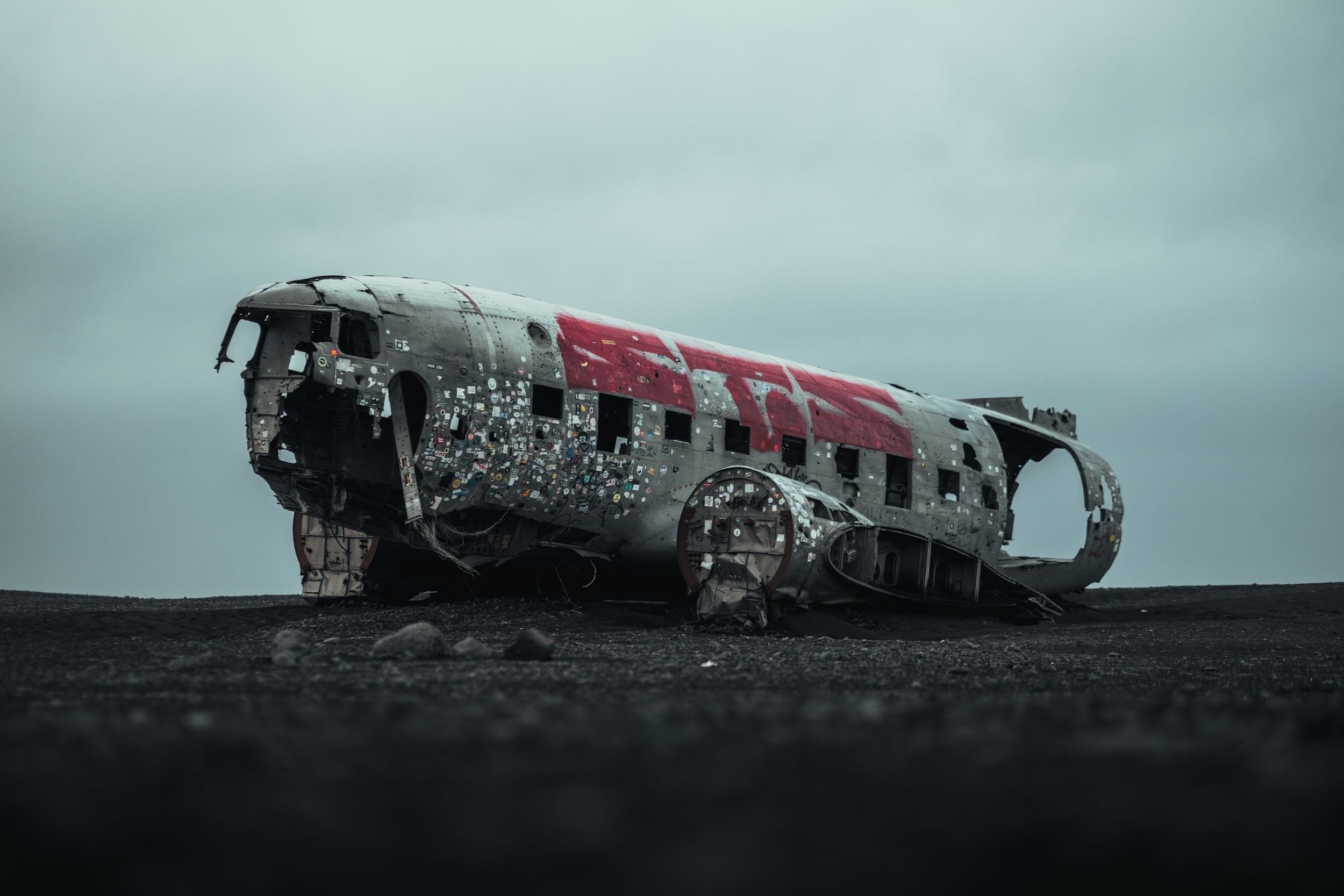 A crashed airplane remains on a barren, rocky landscape under a cloudy sky.