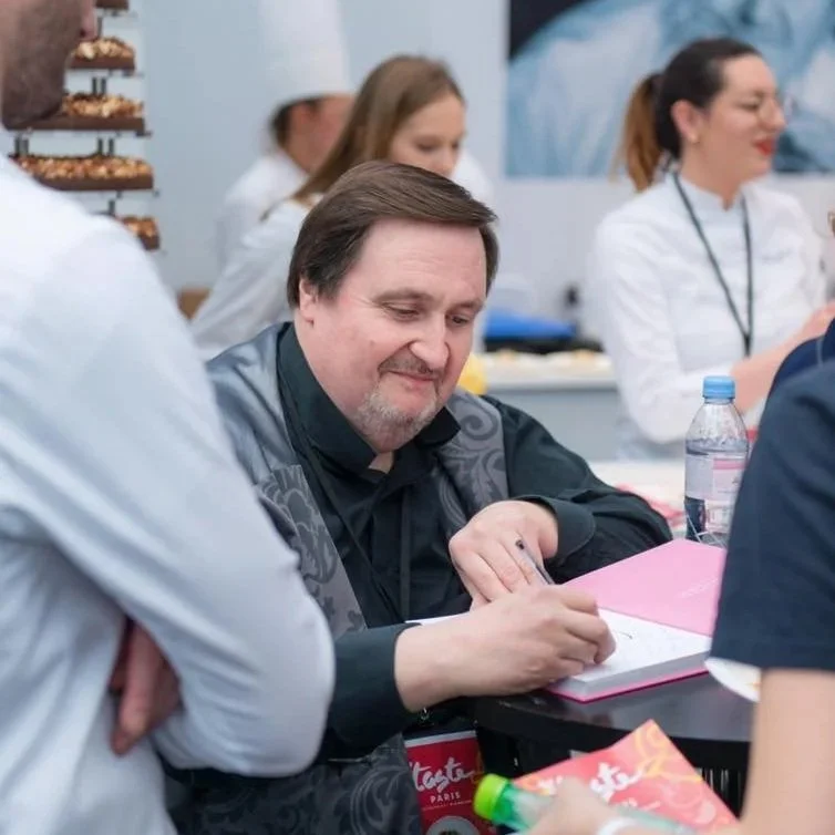 Le chef Philippe Conticini en train de signer un livre entouré de sa brigade lors du festival éphémère Taste of Paris.