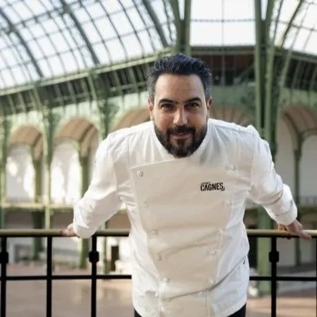 Portrait du chef pâtissier Jeffrey Cagnes en veste blanche de cuisine posant sous la nef historique du Grand Palais lors de Taste of Paris.