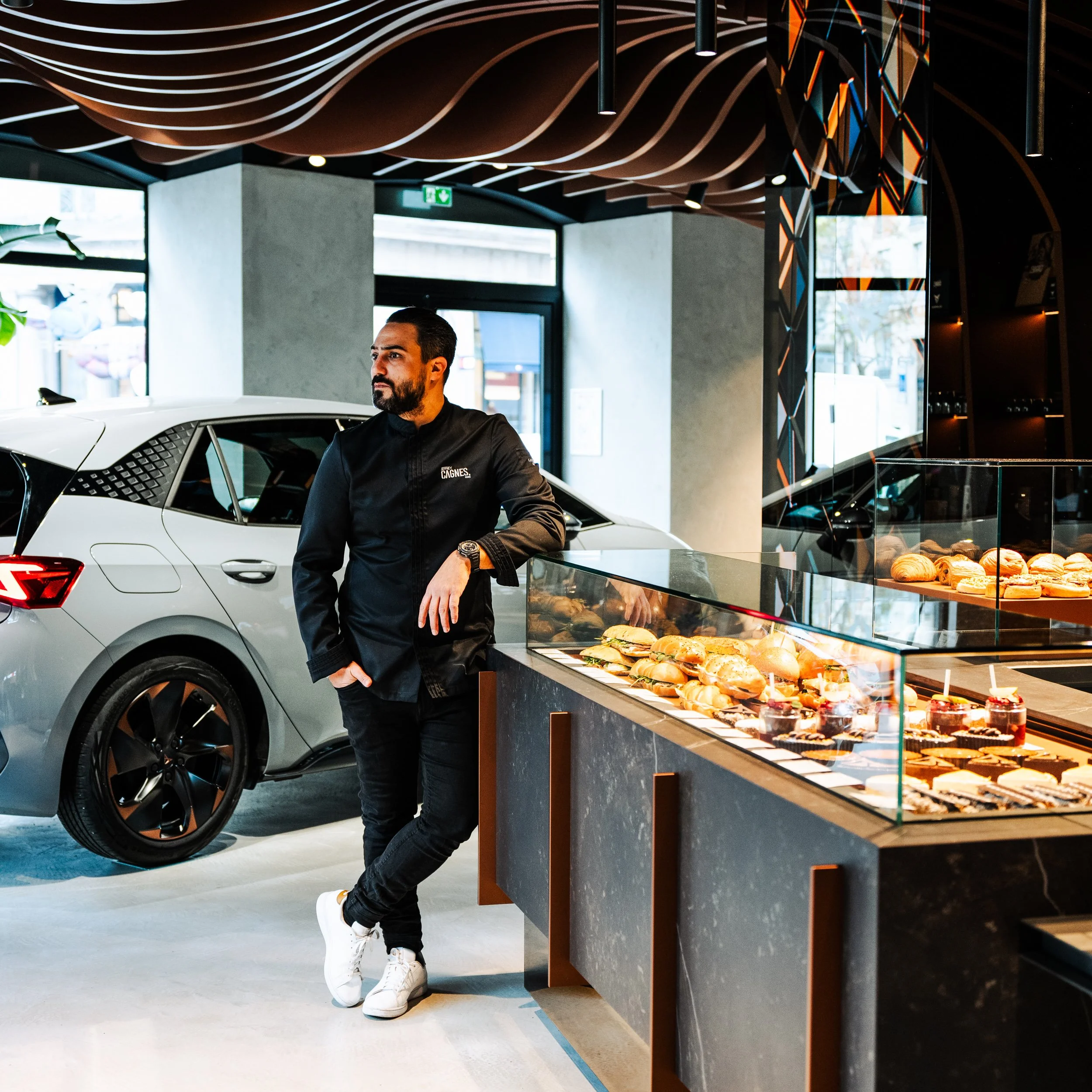 Jeffrey Cagnes adossé au comptoir en marbre noir de son espace pâtisserie sur-mesure au sein du flagship automobile Cupra à Paris.