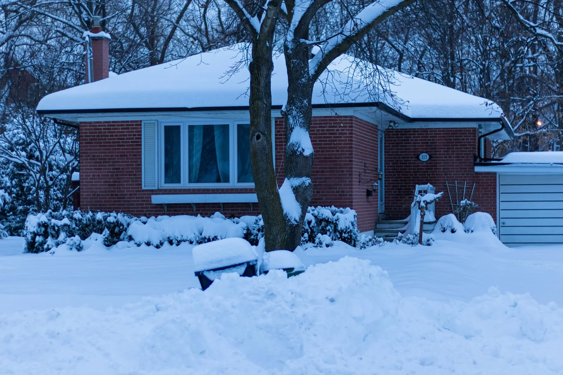 Ice dam and icicles along the eaves of a snow-covered roof on a Kitchener-Waterloo home in winter