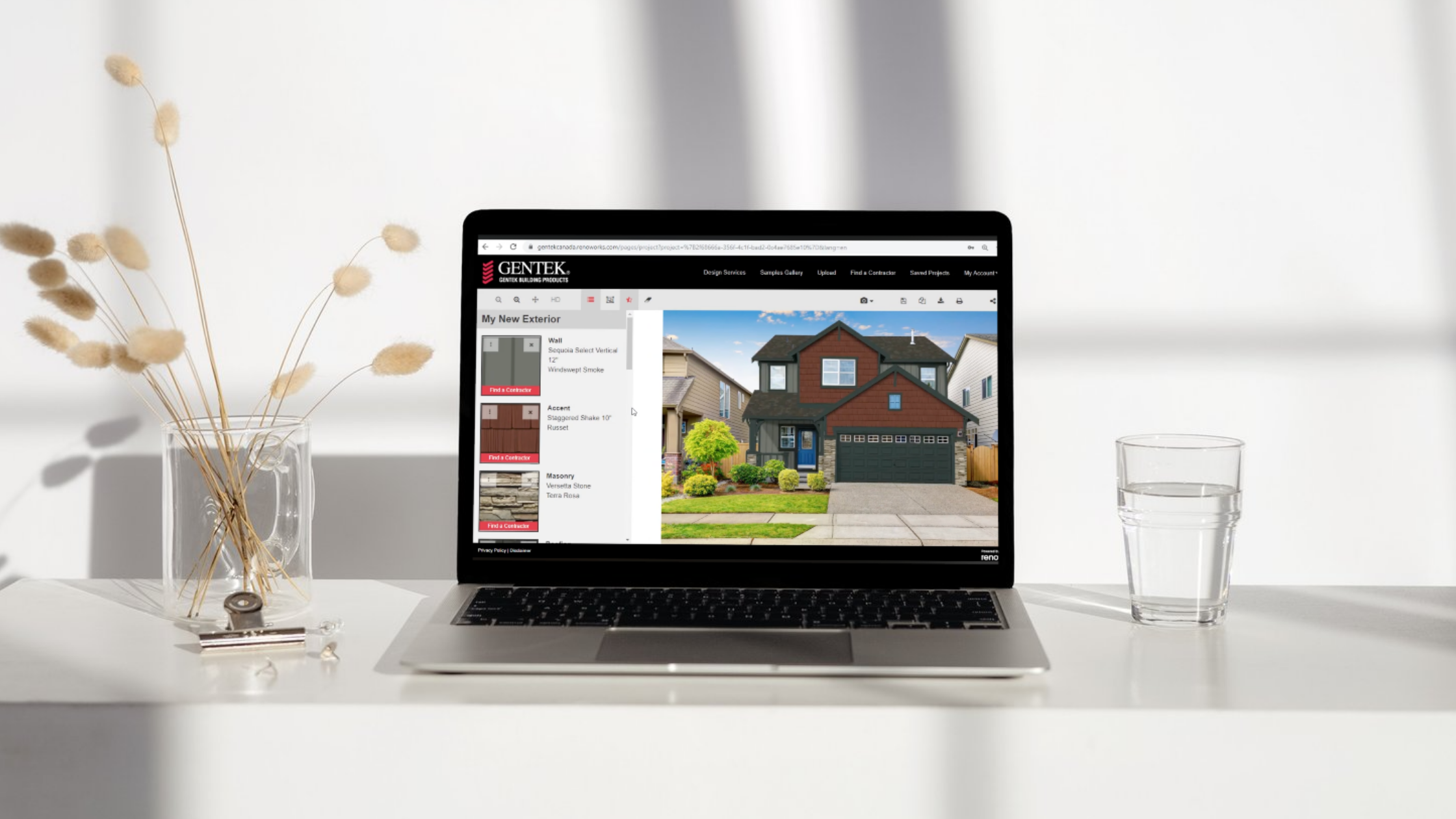 Laptop on white surface displaying a home exterior design website, with a house picture and design options. To the left, a vase with dried beige flowers, and to the right, a glass of water.