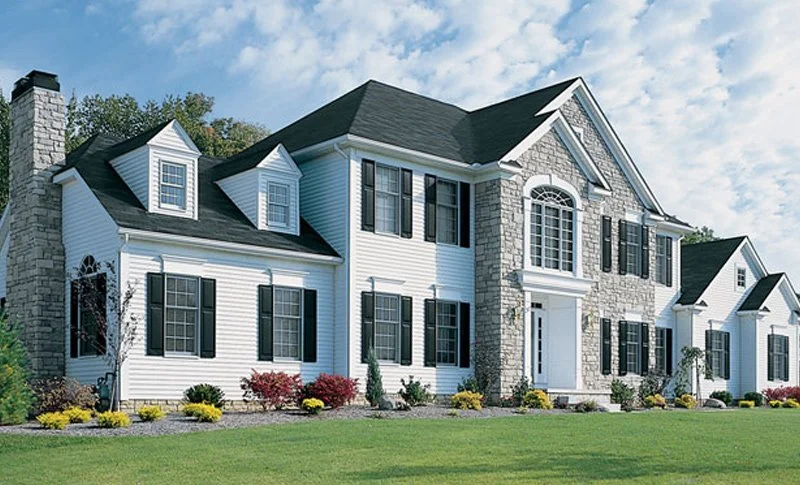 Large white house with black shutters, stone accents, and multiple gables.