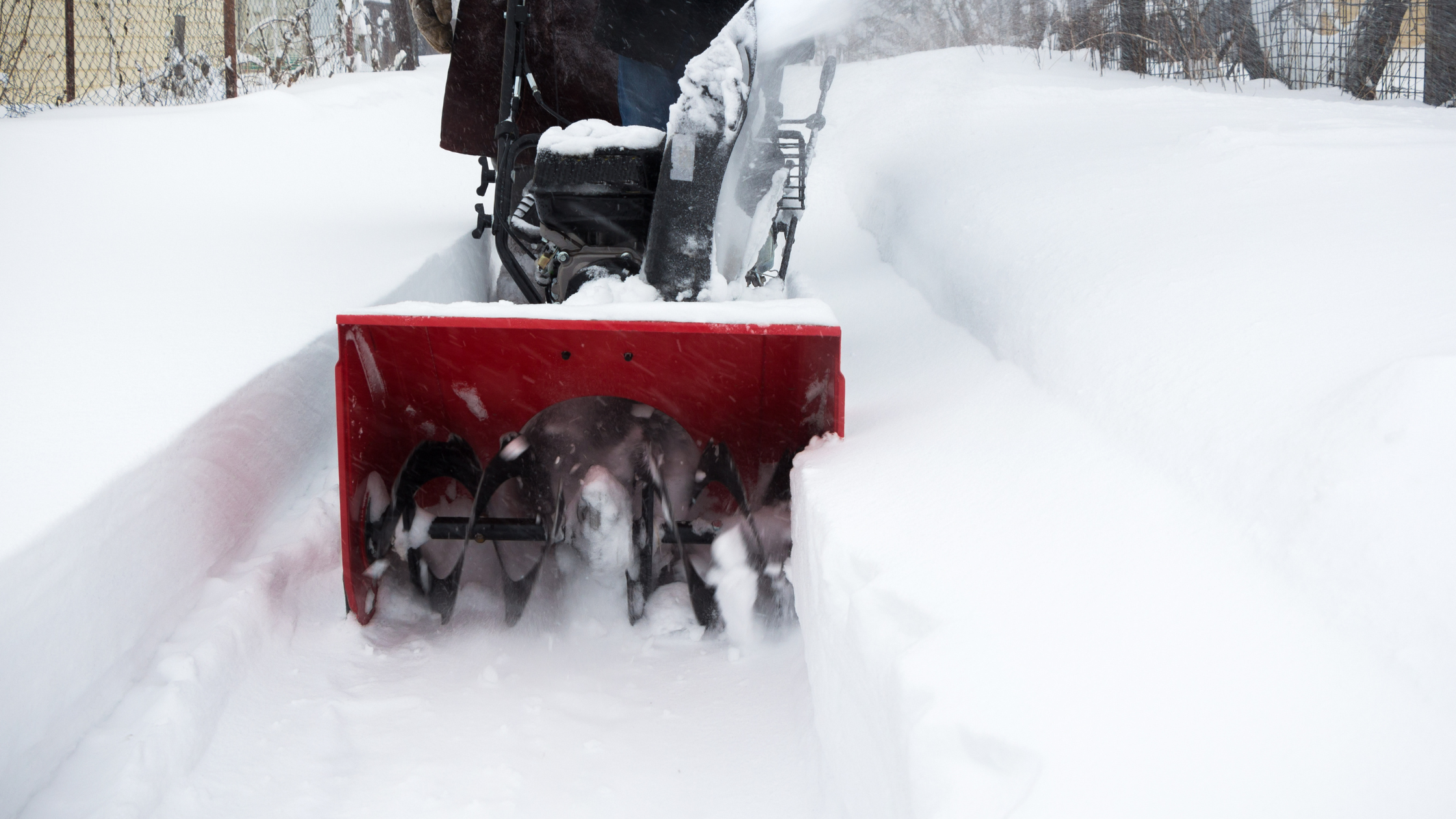 A snowblower clearing snow from a path in a snowy outdoor area.