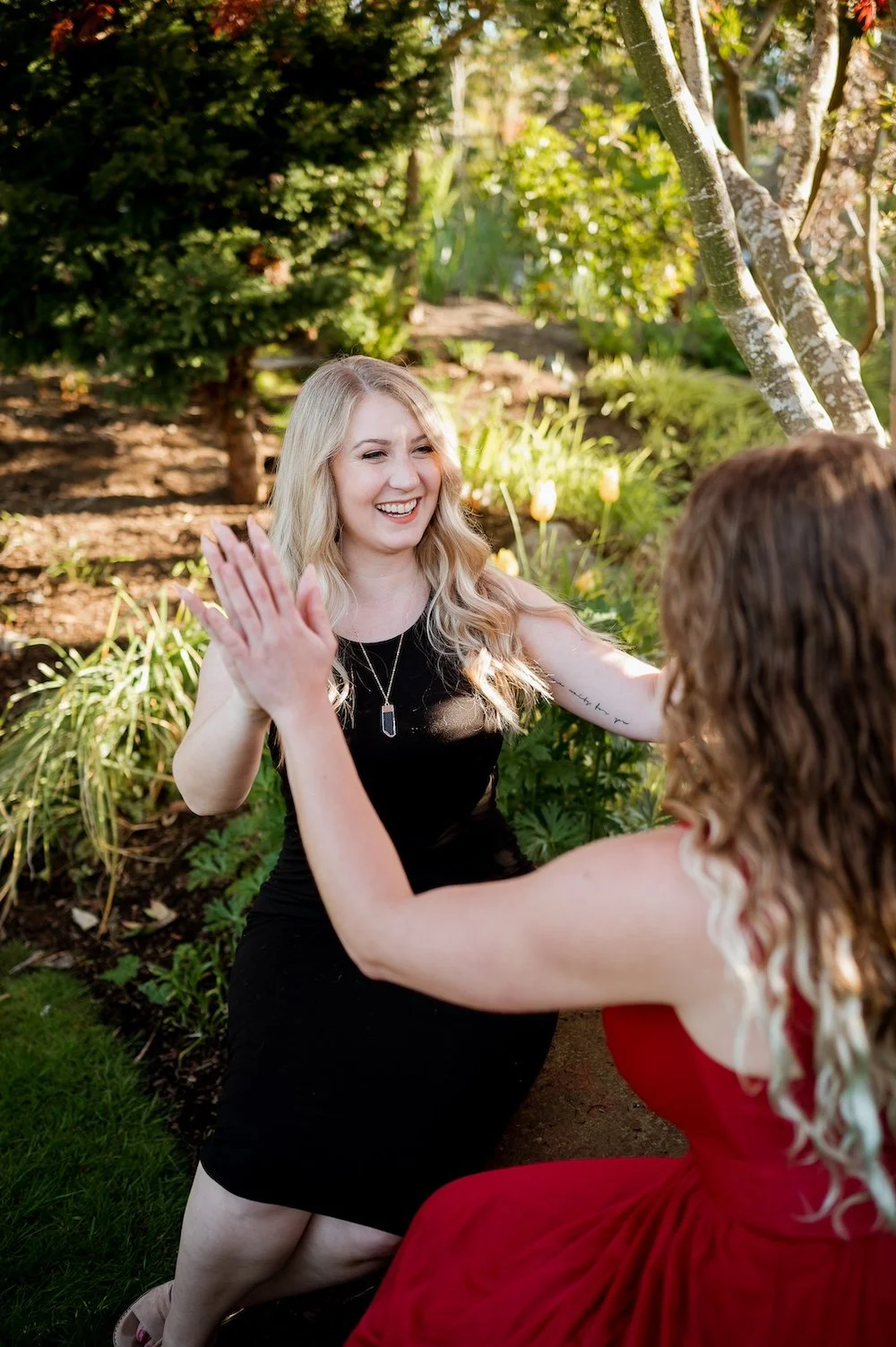 a woman facing the camera touching hands with another woman facing away from the camera